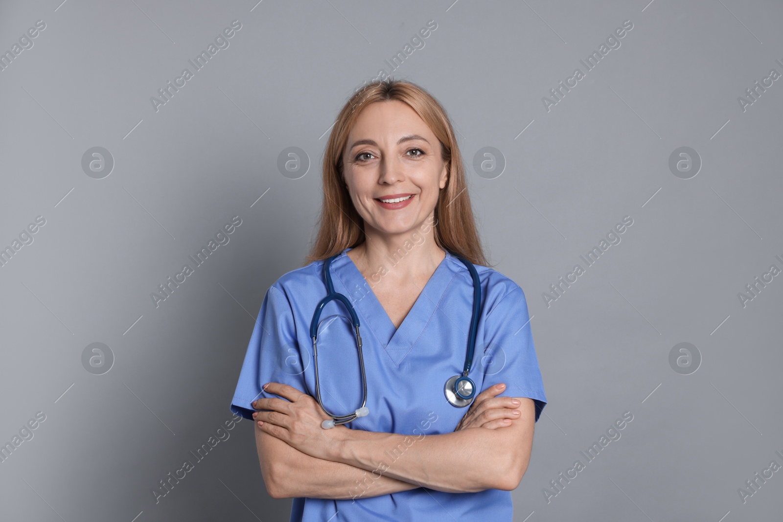 Photo of Smiling doctor with stethoscope on gray background