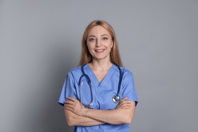 Smiling doctor with stethoscope on gray background