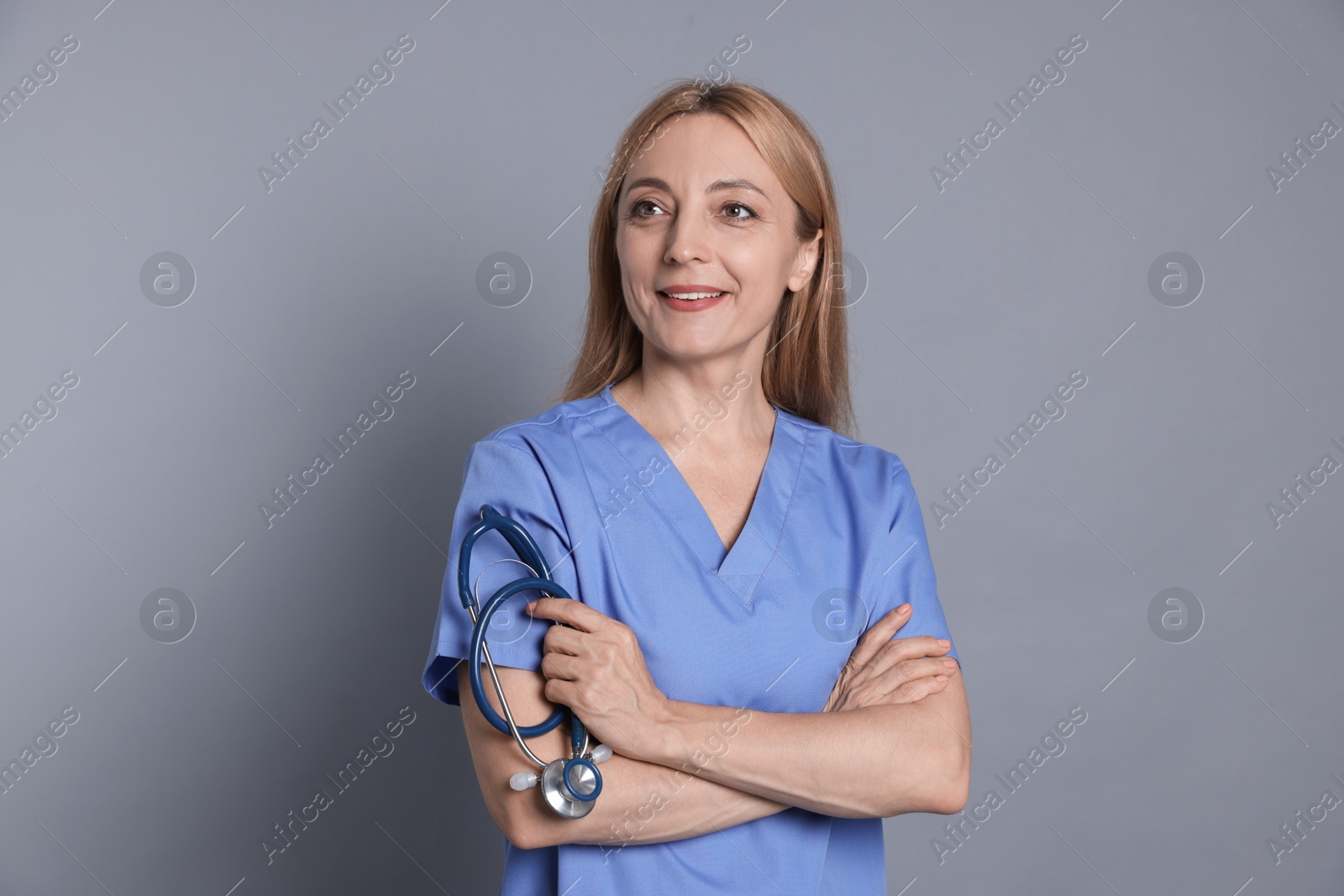 Photo of Smiling doctor with stethoscope on gray background