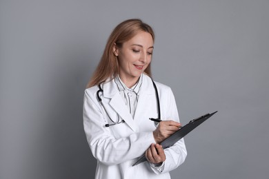 Photo of Doctor with clipboard writing notes on gray background