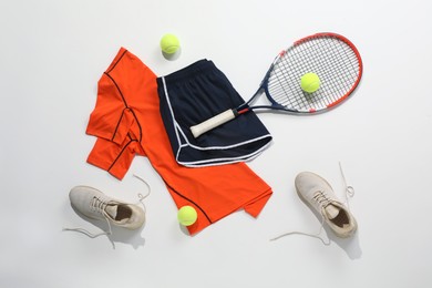 Photo of Tennis racket, balls, sneakers and sportswear on light background, flat lay