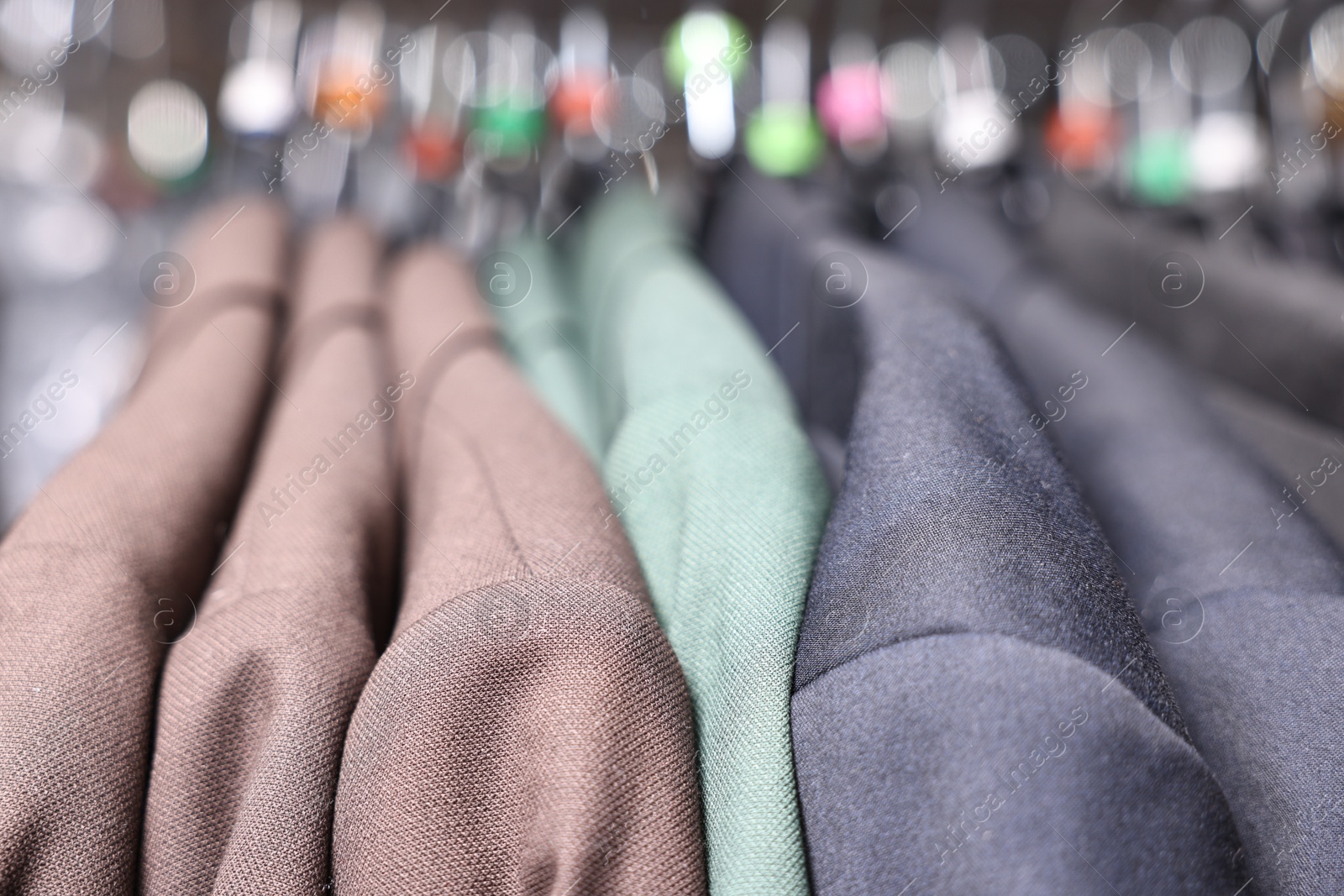 Photo of Many different clothes hanging from rack in professional workshop, closeup