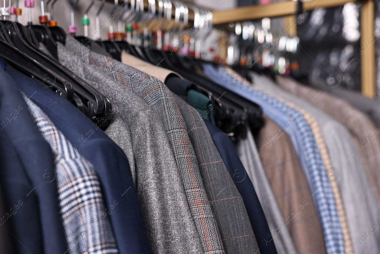 Photo of Many different clothes hanging from rack in professional workshop, closeup