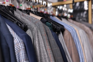 Photo of Many different clothes hanging from rack in professional workshop, closeup