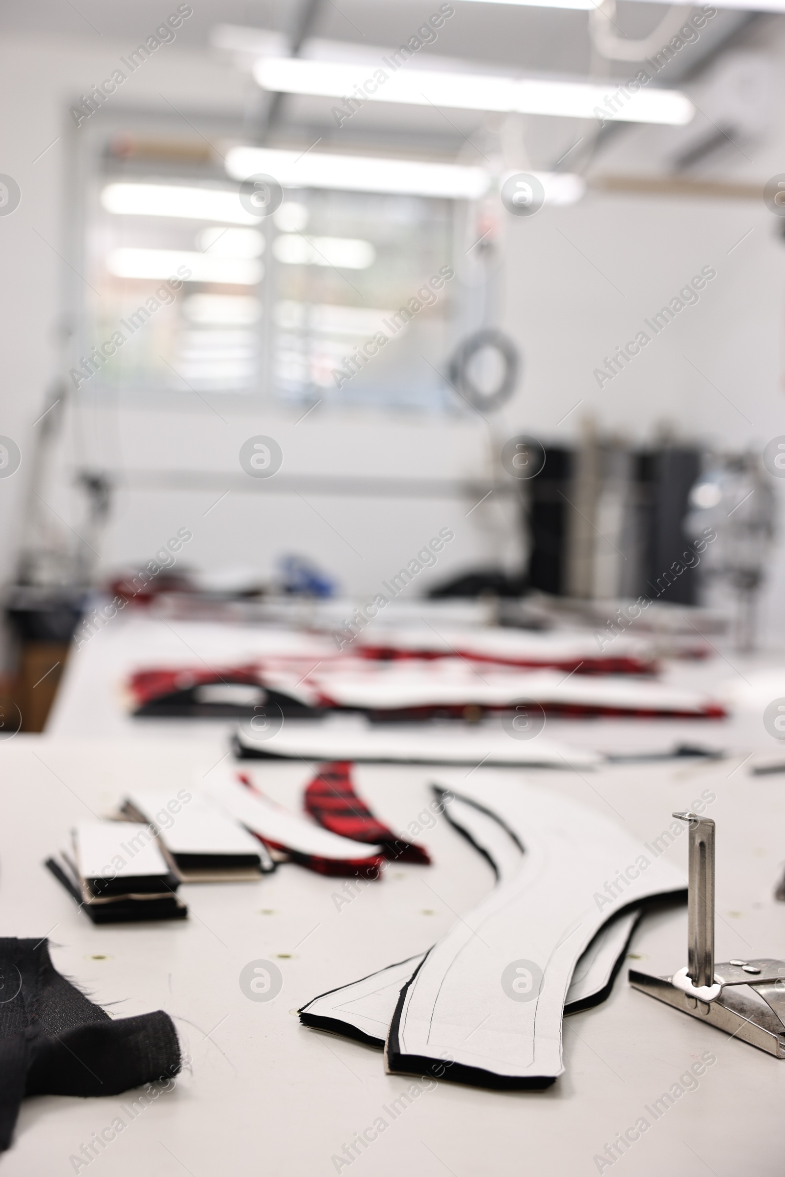 Photo of Professional workshop with different fabrics, white table and tools