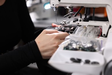 Photo of Woman working with sewing machine in professional workshop, closeup