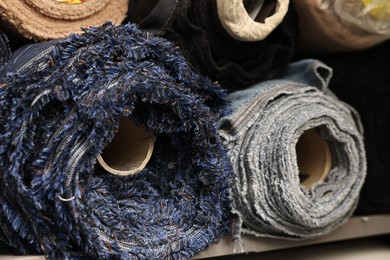 Photo of Many different types of fabric on shelves in professional workshop, closeup