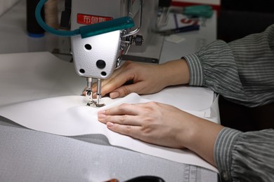 Photo of Woman working with sewing machine in professional workshop, closeup