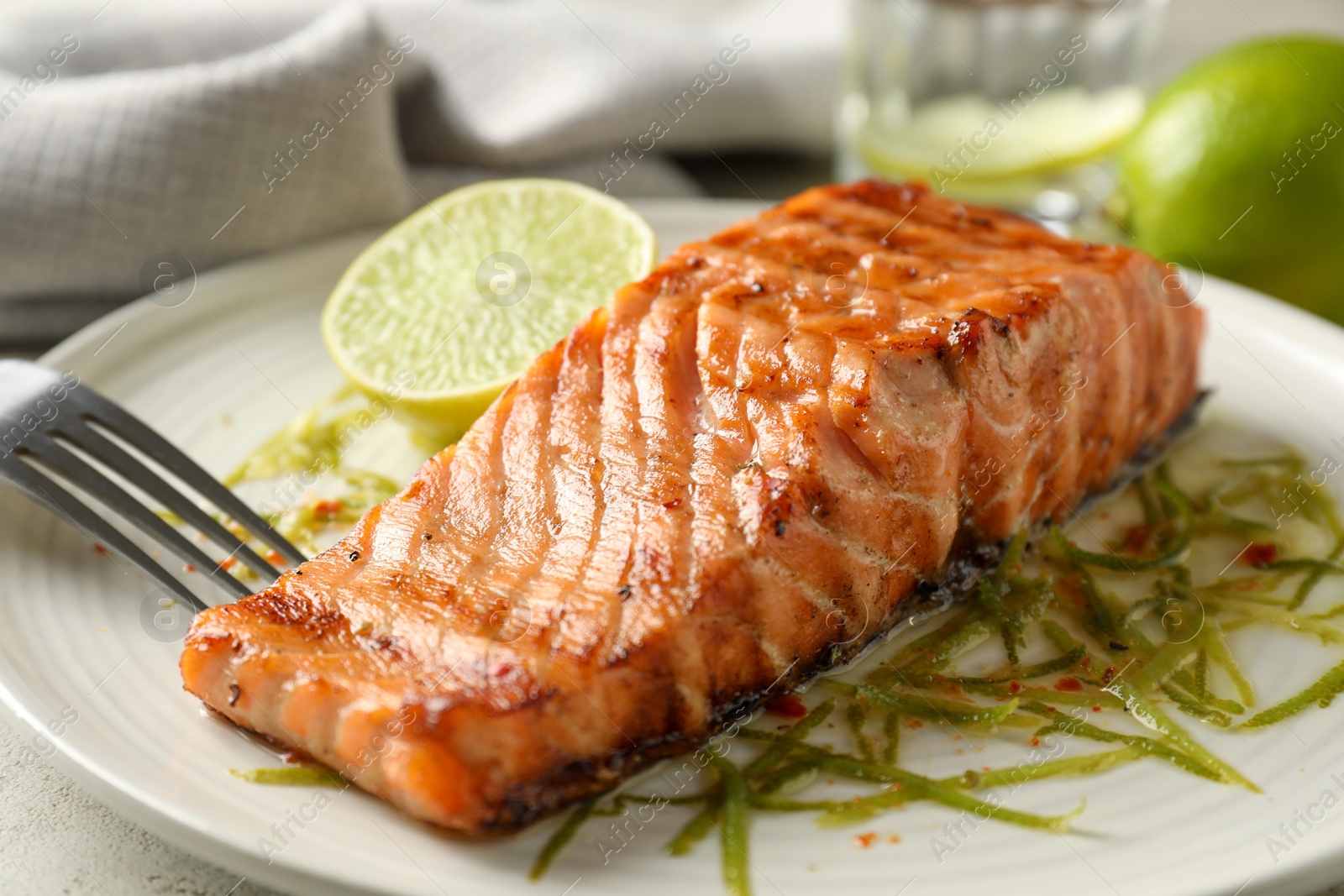 Photo of Delicious grilled salmon fillet served on light table, closeup