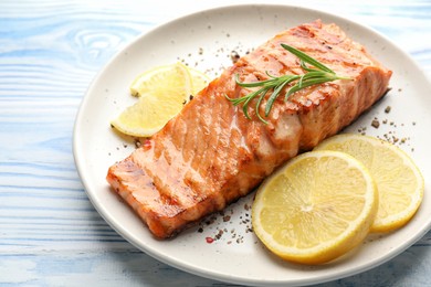 Photo of Delicious grilled salmon fillet served on light blue wooden table, closeup