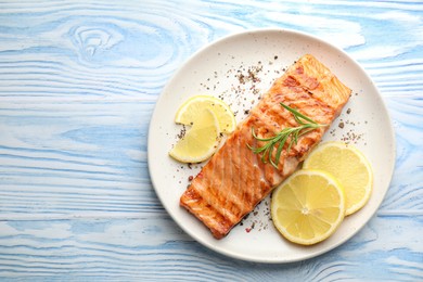 Photo of Delicious grilled salmon fillet served on light blue wooden table, top view