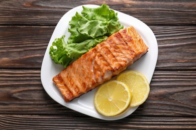 Photo of Delicious grilled salmon fillet served on wooden table, top view