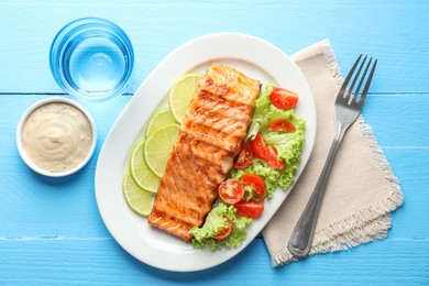 Photo of Delicious grilled salmon fillet served on light blue wooden table, flat lay