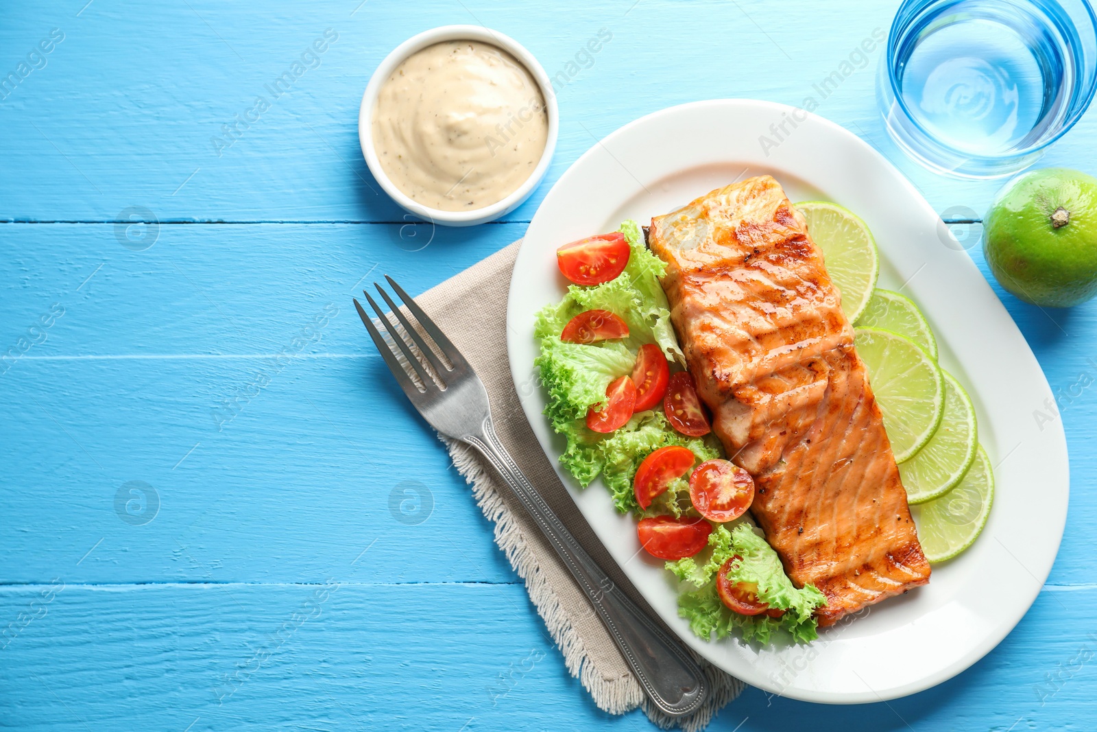 Photo of Delicious grilled salmon fillet served on light blue wooden table, flat lay. Space for text