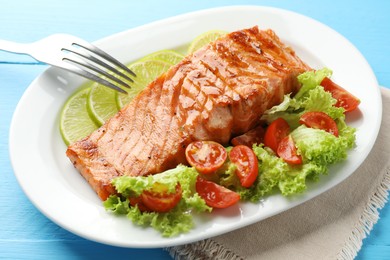 Photo of Delicious grilled salmon fillet served on light blue wooden table, closeup