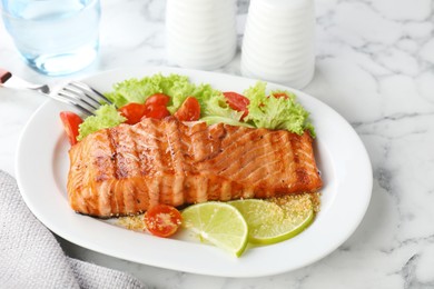 Photo of Delicious grilled salmon fillet served on white marble table