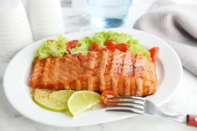 Photo of Delicious grilled salmon fillet served on white marble table, closeup