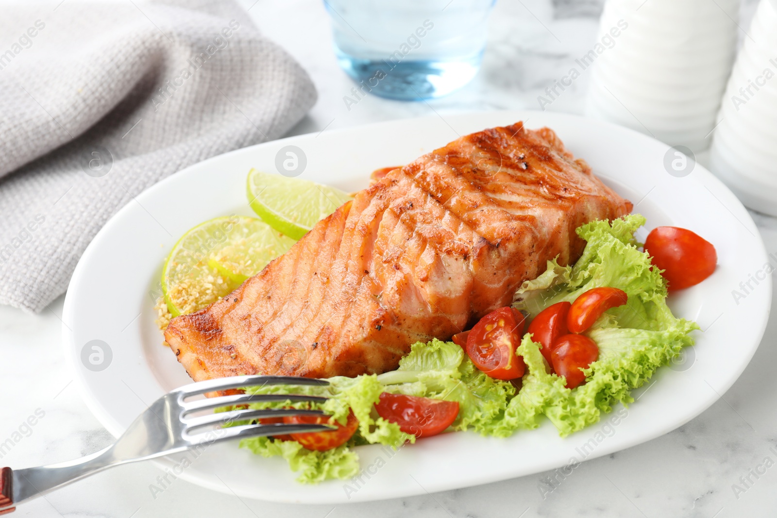 Photo of Delicious grilled salmon fillet served on white marble table, closeup