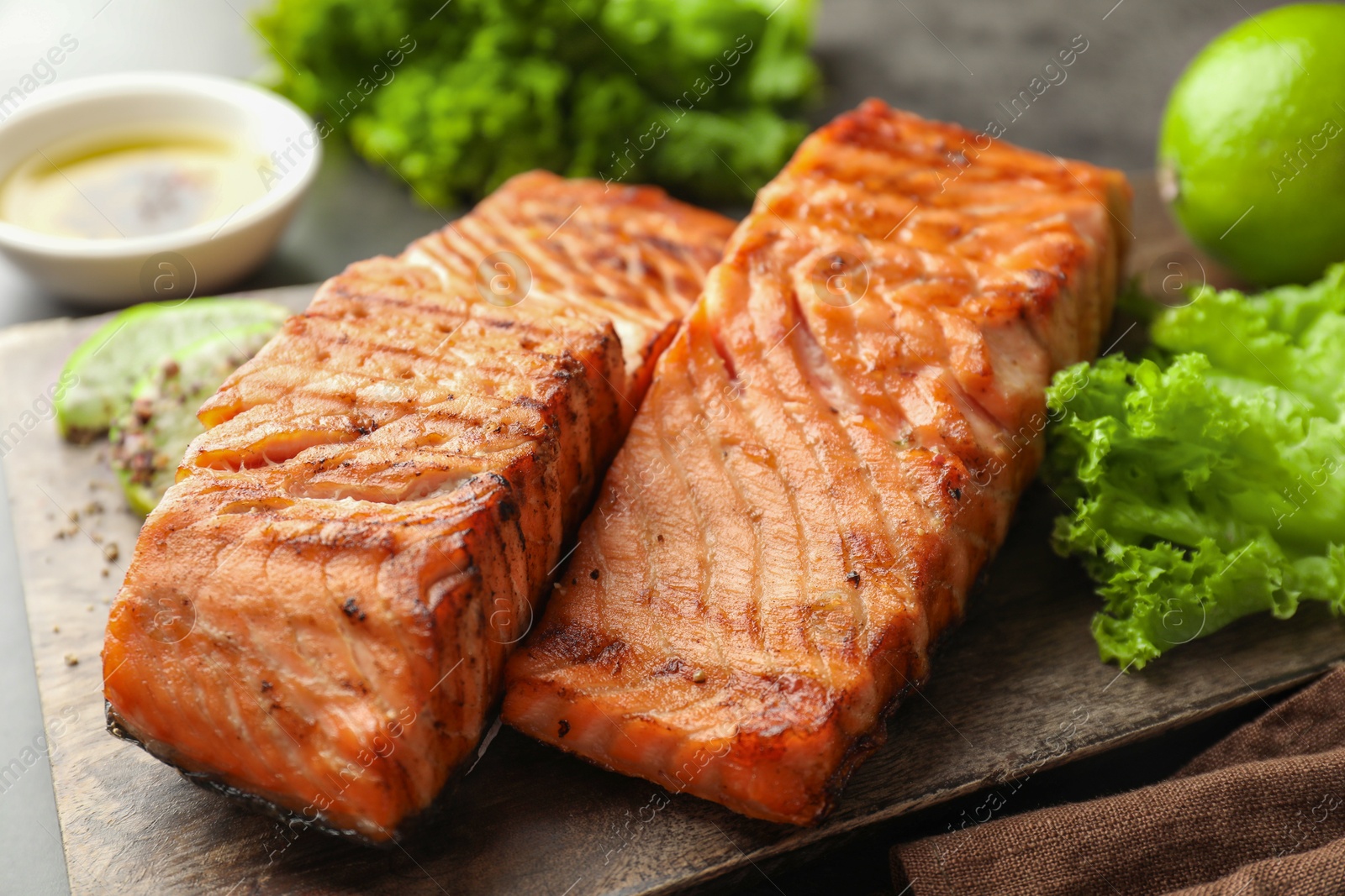 Photo of Delicious grilled salmon fillets served on grey table, closeup