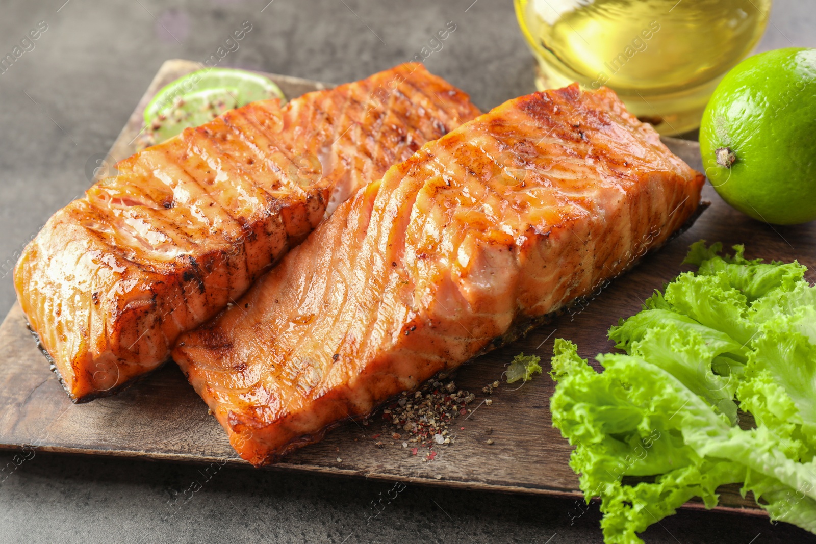 Photo of Delicious grilled salmon fillets served on grey table, closeup