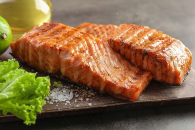 Photo of Delicious grilled salmon fillets served on grey table, closeup