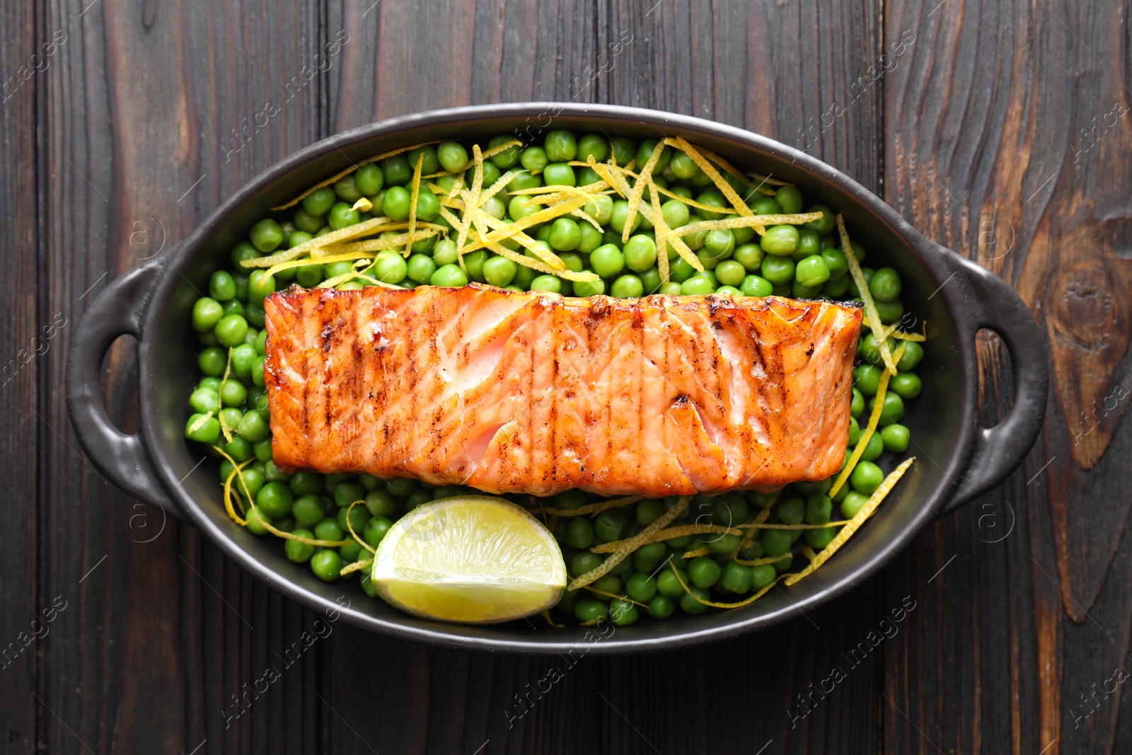 Photo of Delicious grilled salmon fillet with green peas and lime in baking dish on wooden table, top view