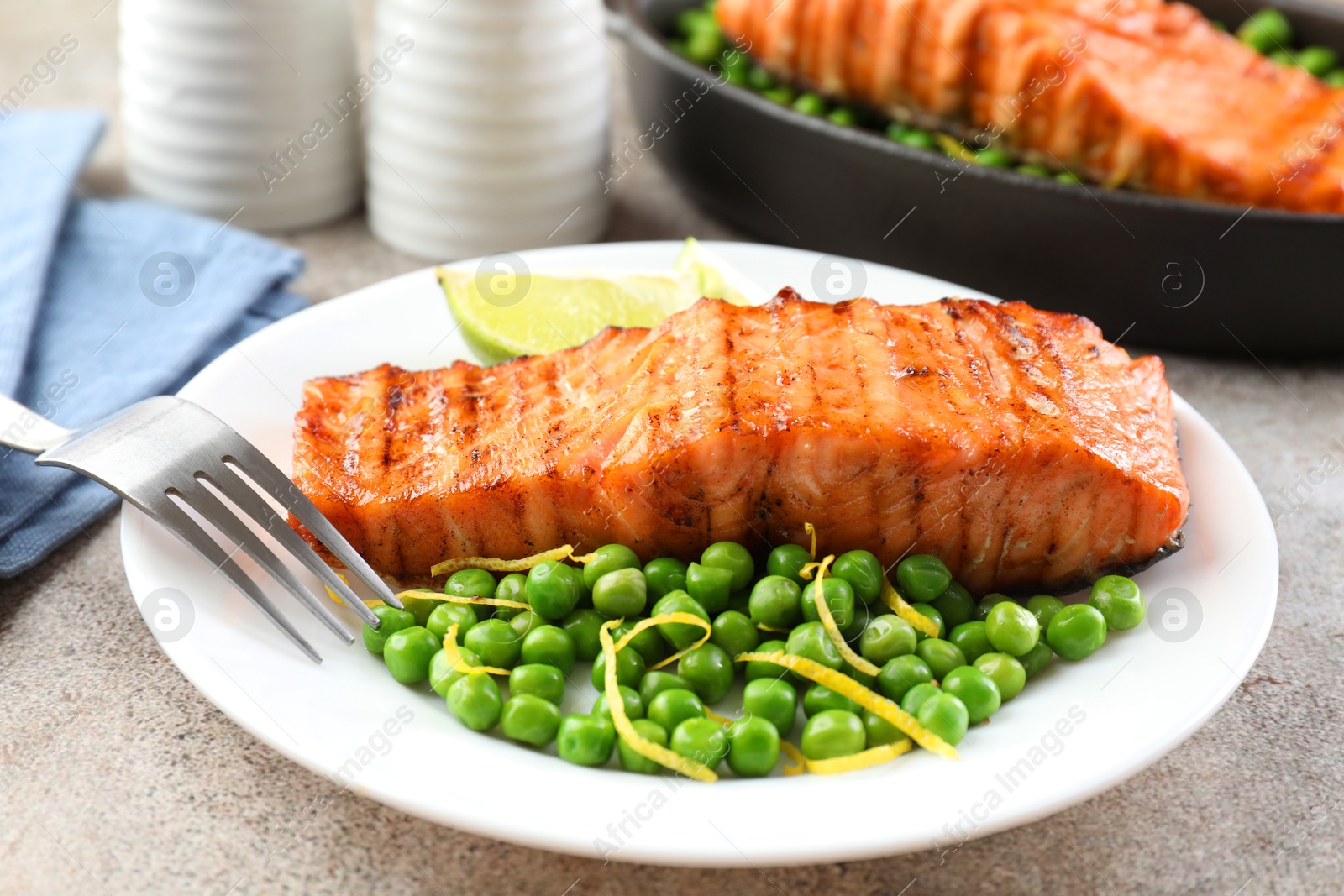 Photo of Delicious grilled salmon fillet served on grey textured table, closeup