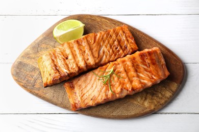 Photo of Delicious grilled salmon fillets with lime and rosemary on white wooden table, top view