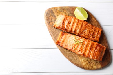 Photo of Delicious grilled salmon fillets with lime and rosemary on white wooden table, top view. Space for text