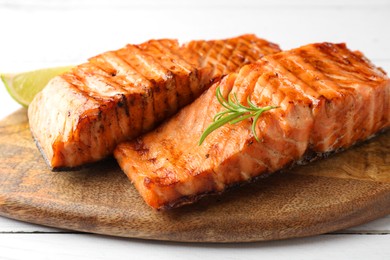 Photo of Delicious grilled salmon fillets with rosemary on white wooden table, closeup