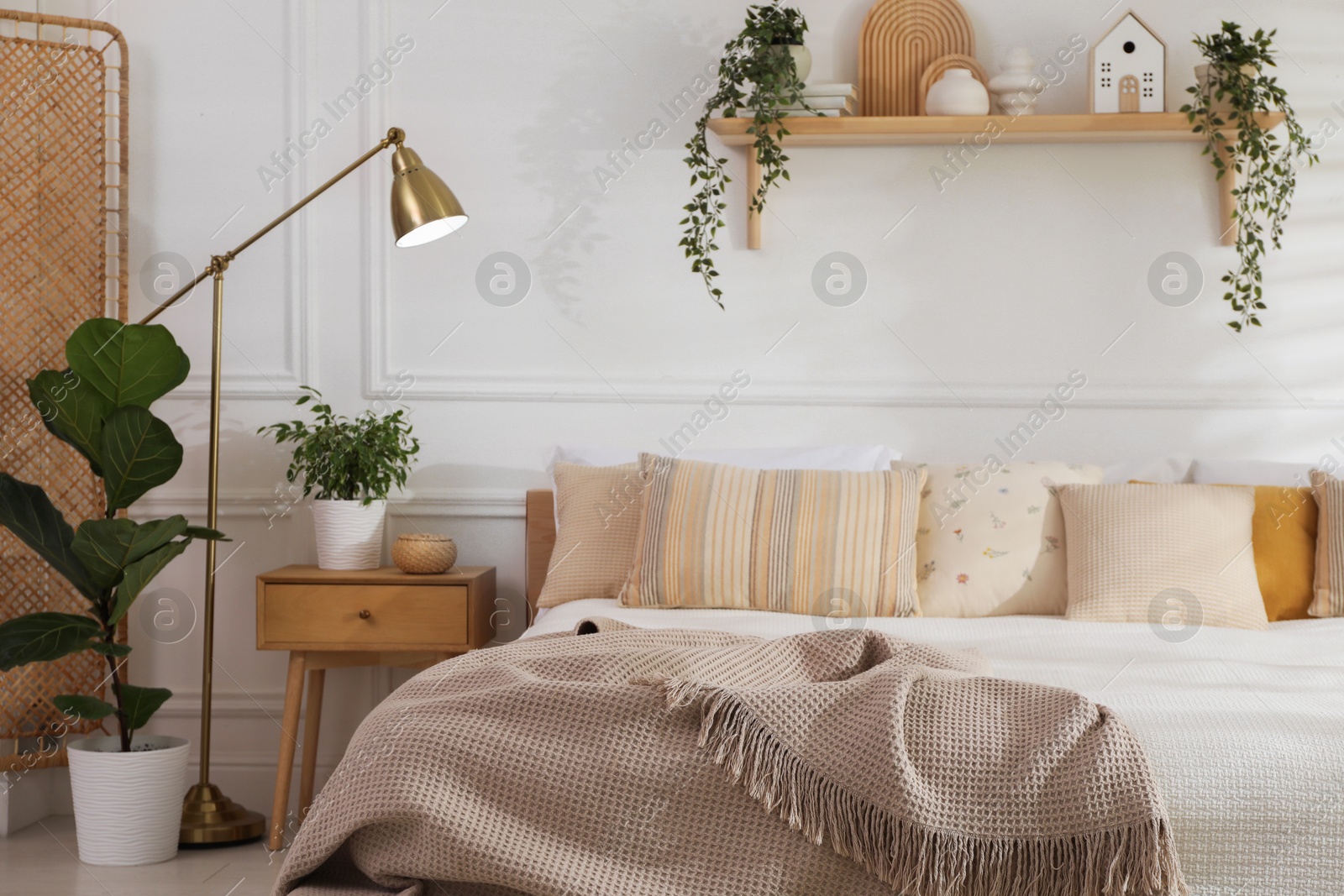 Photo of Stylish bedroom interior with large bed, houseplants and decorative elements