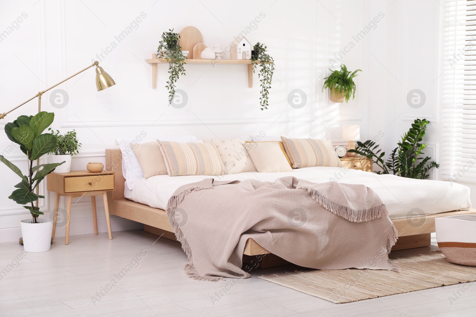 Photo of Stylish bedroom interior with large bed, houseplants and decorative elements