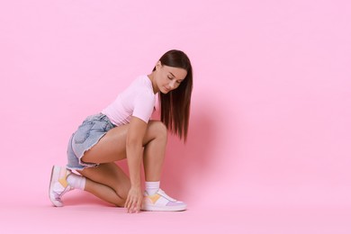 Beautiful woman wearing stylish denim shorts on pink background, space for text