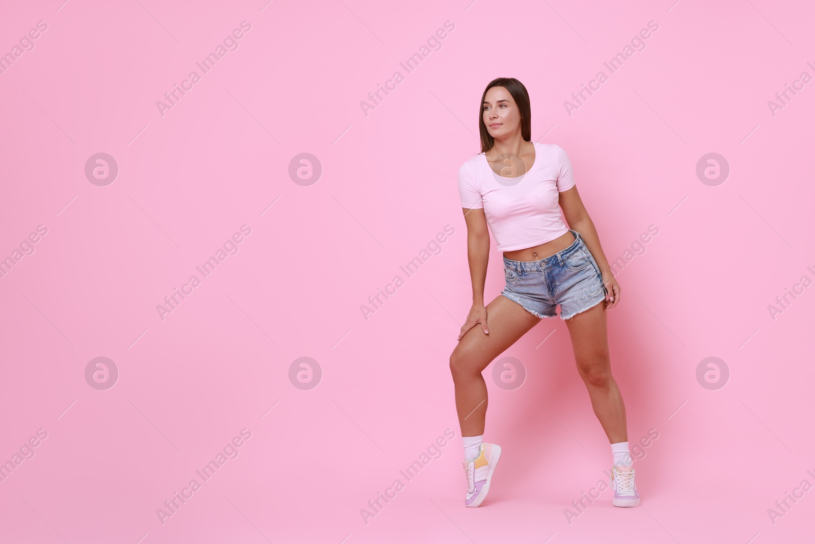 Photo of Beautiful woman wearing stylish denim shorts on pink background