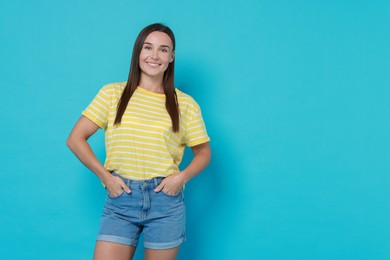 Beautiful woman wearing stylish denim shorts on light blue background, space for text