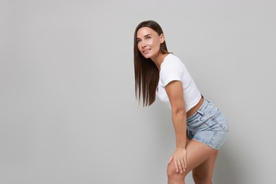 Beautiful woman wearing stylish denim shorts on gray background, space for text