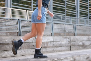 Woman in stylish denim shorts walking outdoors, closeup