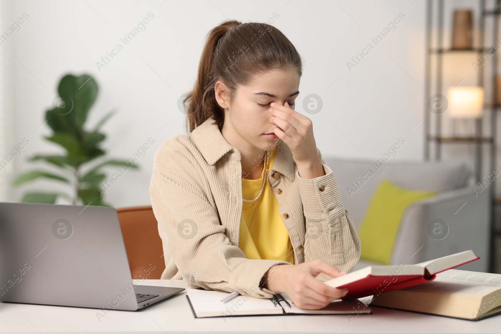 Photo of Tired student preparing for exam at table indoors