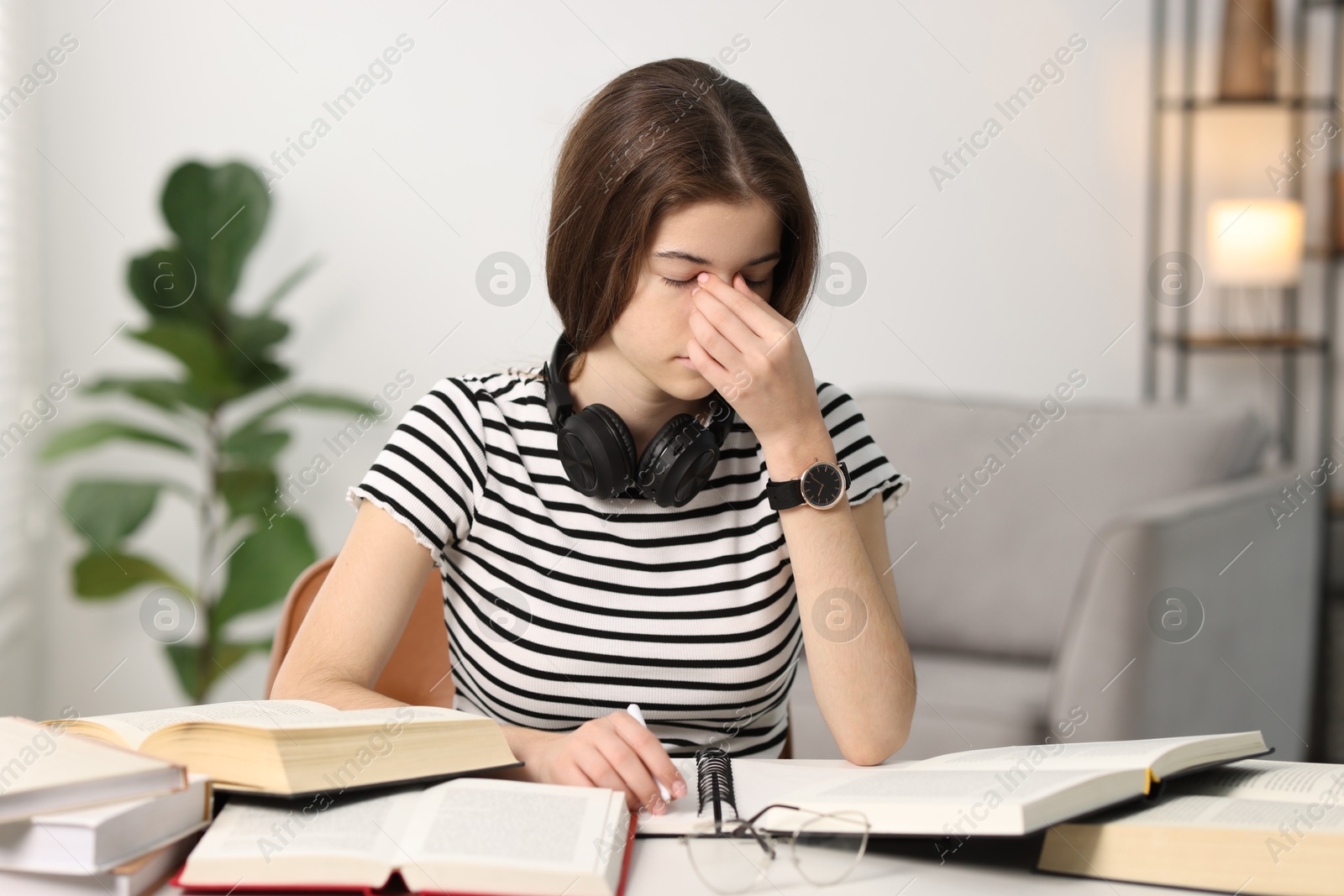 Photo of Preparing for exam. Tired student with books at table indoors