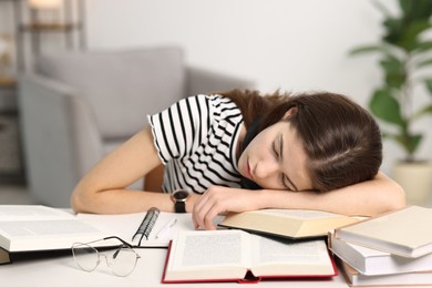 Photo of Preparing for exam. Tired student sleeping among books at table indoors