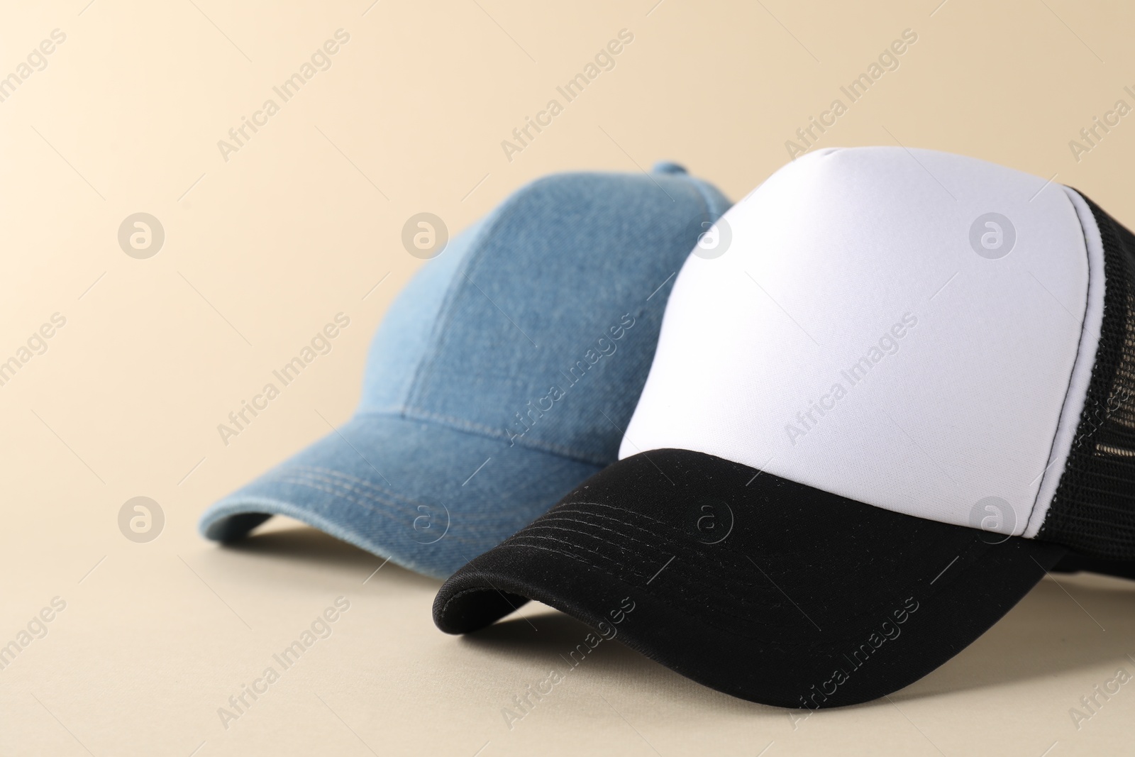 Photo of Stylish baseball caps on beige background, closeup. Mockup for design