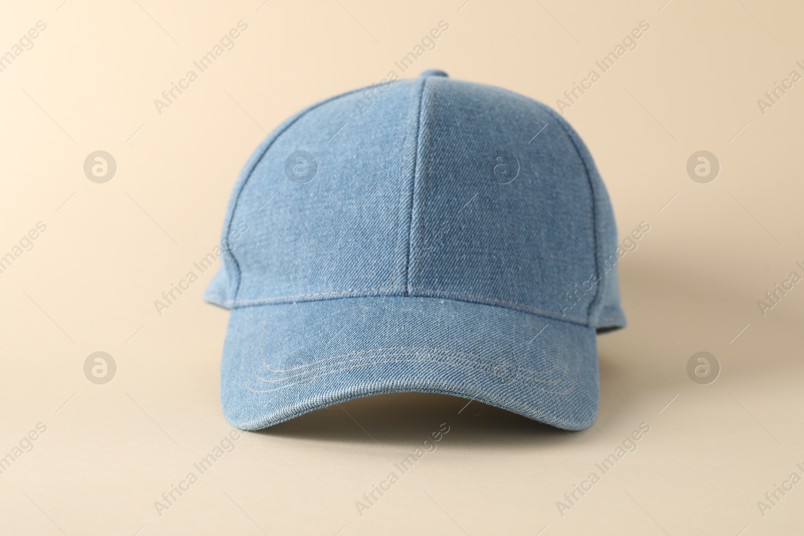 Photo of Stylish denim baseball cap on beige background, closeup. Mockup for design