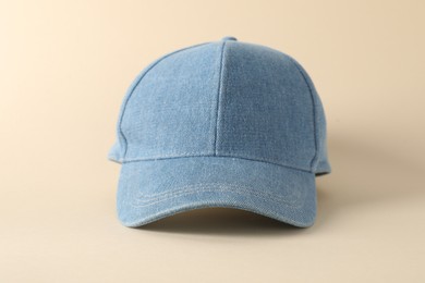 Photo of Stylish denim baseball cap on beige background, closeup. Mockup for design