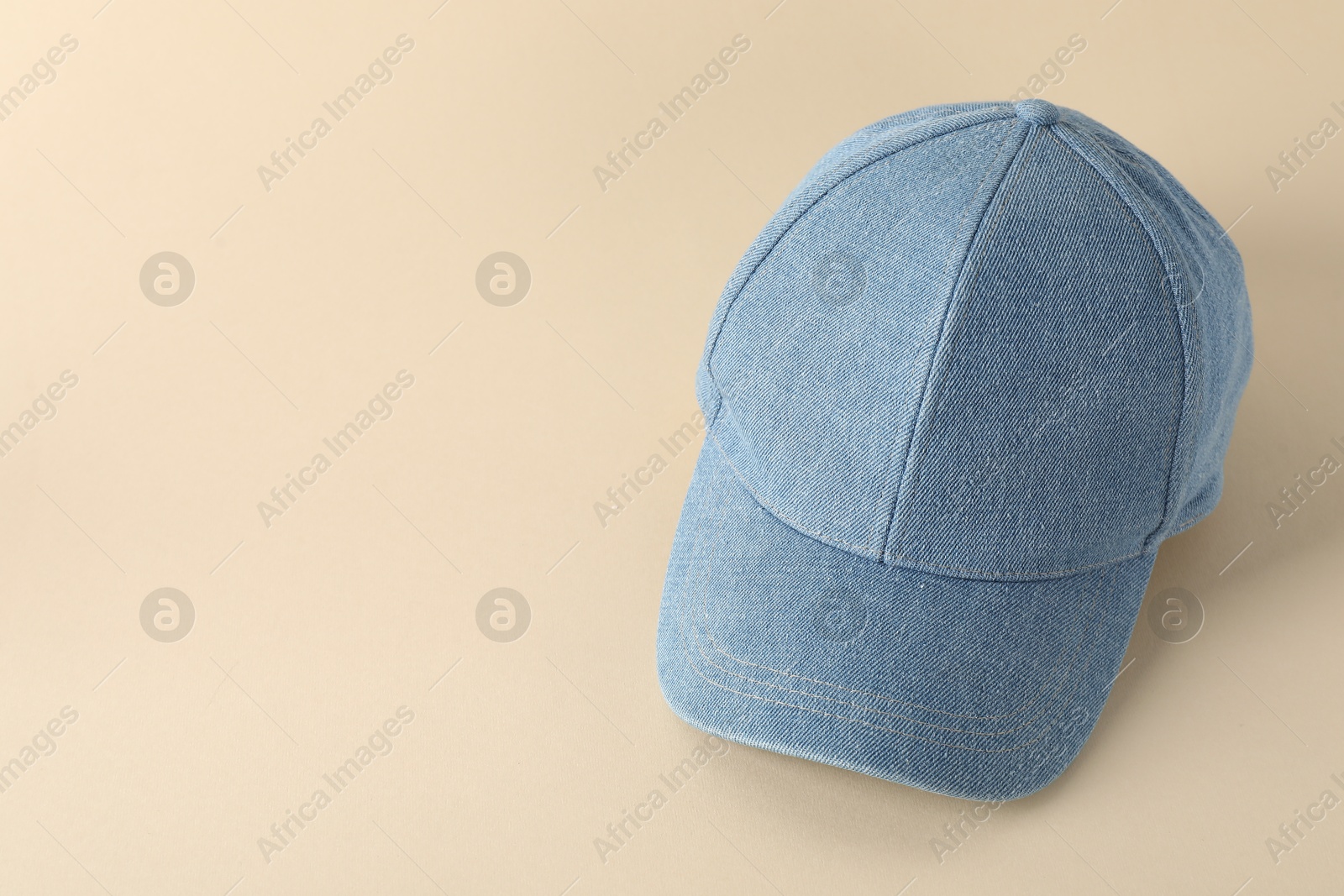 Photo of Stylish denim baseball cap on beige background. Mockup for design