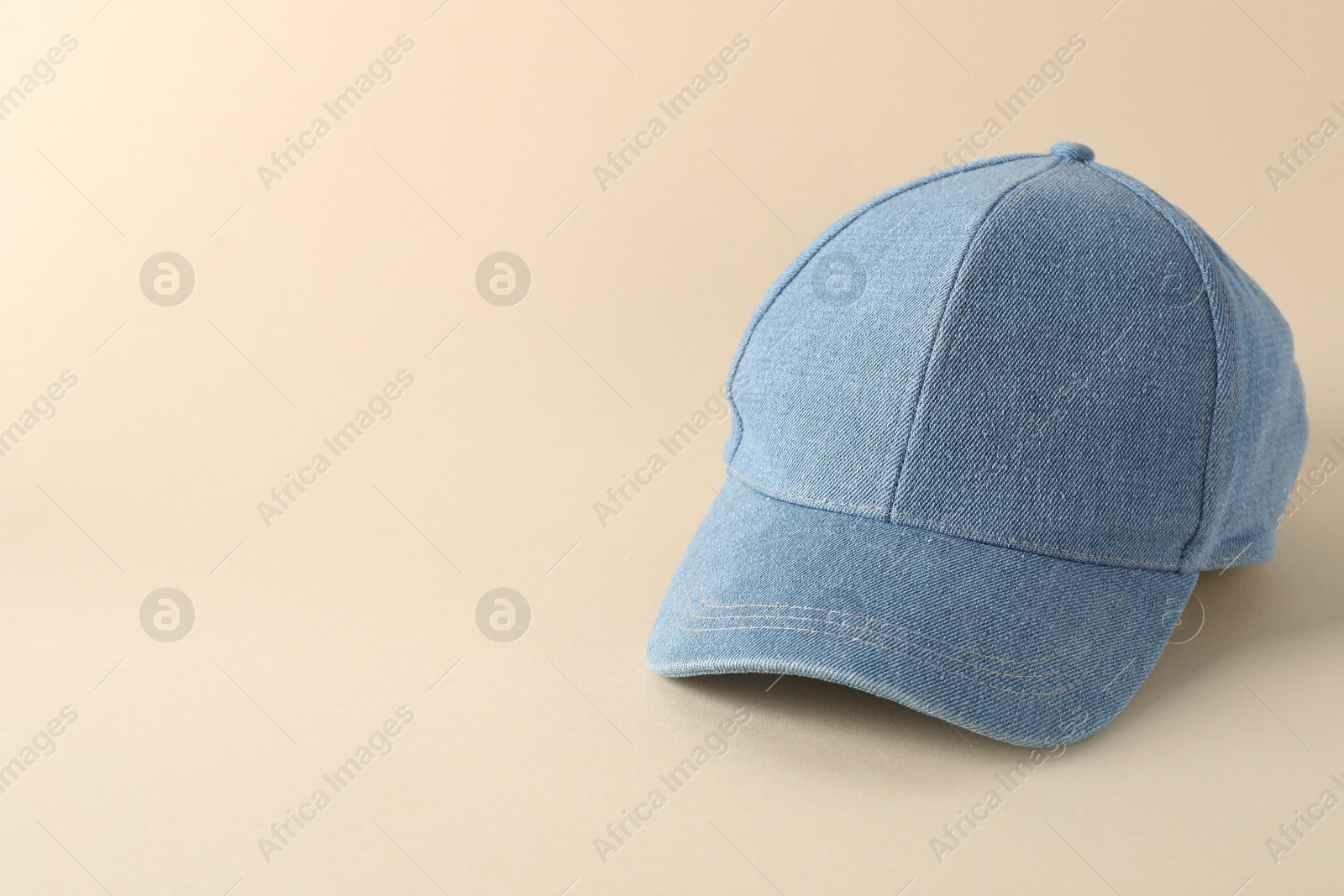 Photo of Stylish denim baseball cap on beige background. Mockup for design