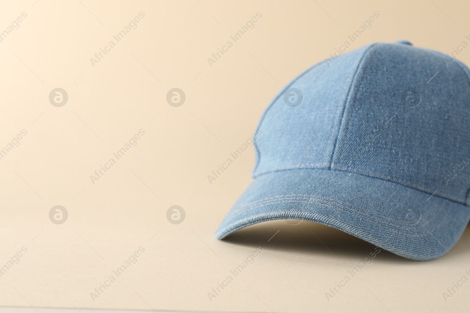 Photo of Stylish denim baseball cap on beige background, closeup. Mockup for design