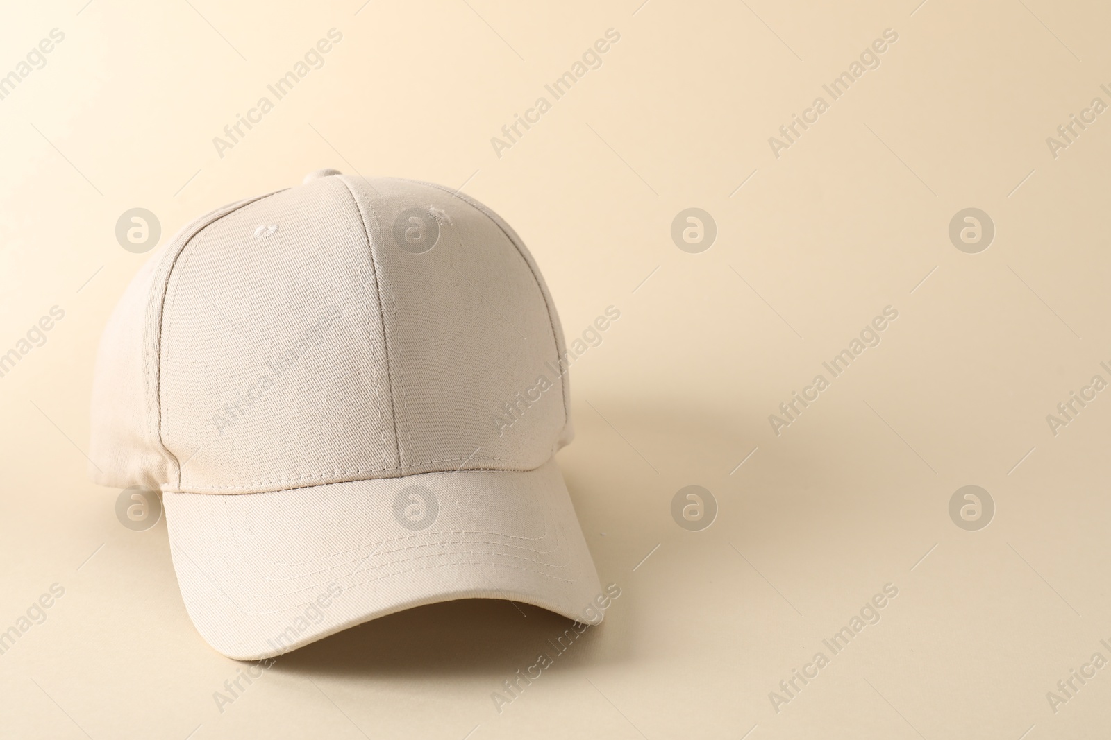 Photo of Stylish baseball cap on beige background. Mockup for design