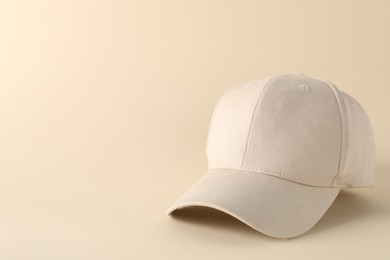 Photo of Stylish baseball cap on beige background. Mockup for design