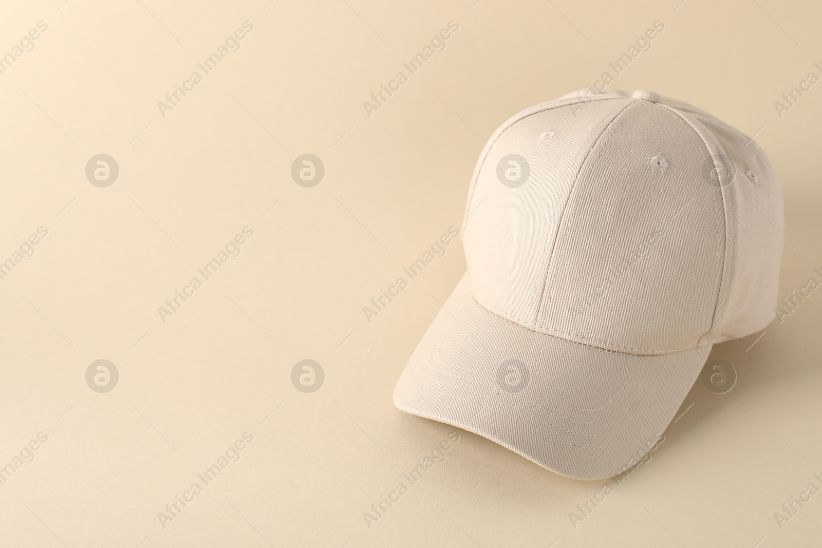 Photo of Stylish baseball cap on beige background. Mockup for design