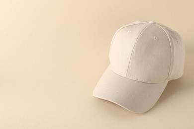 Photo of Stylish baseball cap on beige background. Mockup for design